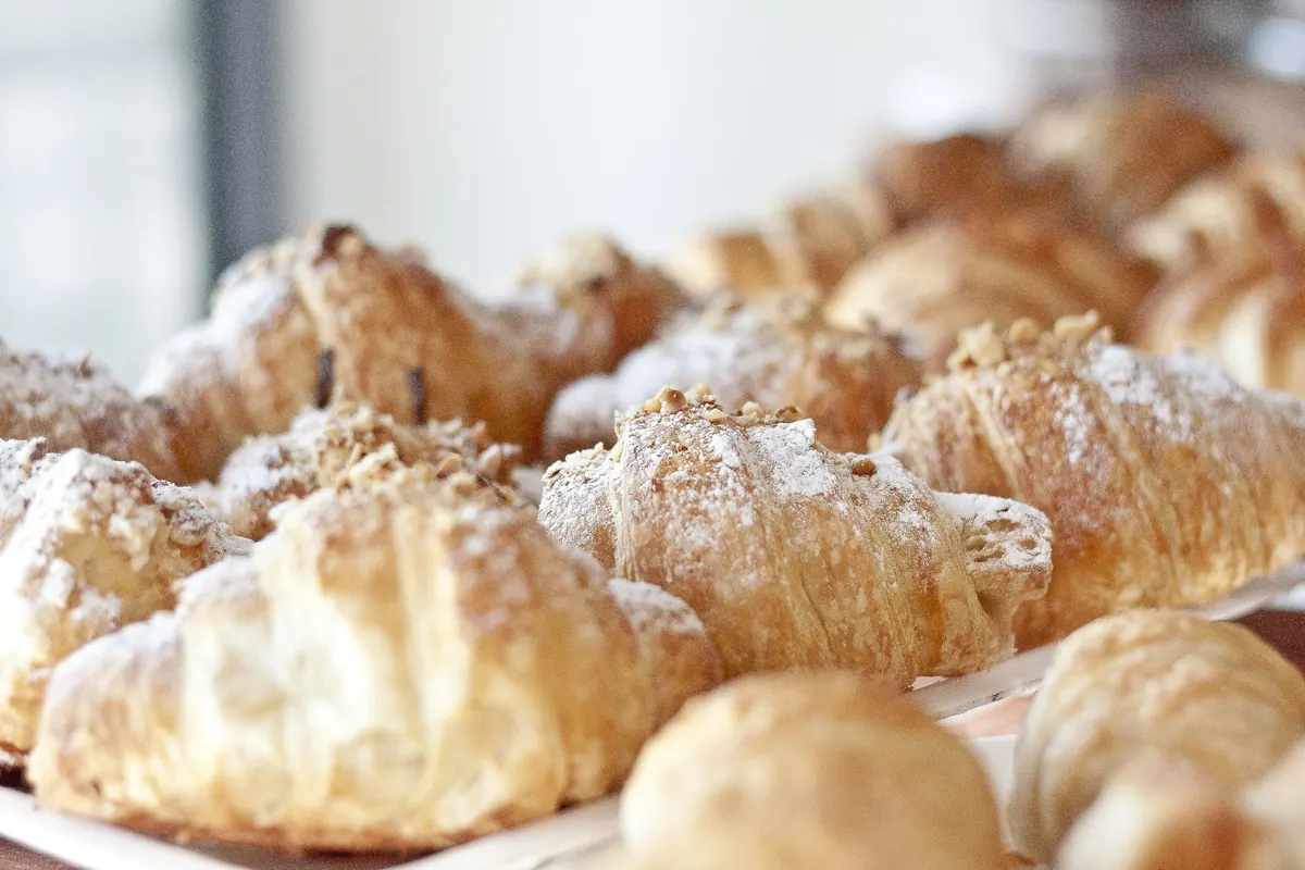 Croissants aux amandes saupoudrés de sucre glace, alignés sur un plateau