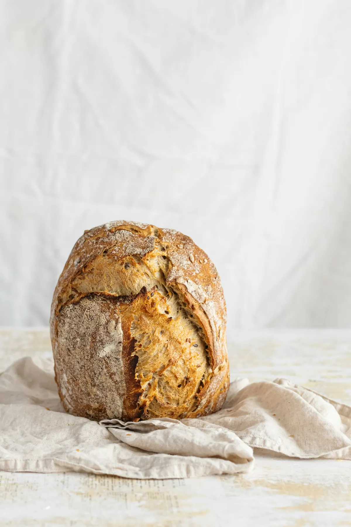 Miche au levain à la croûte dorée, posée sur un torchon de lin