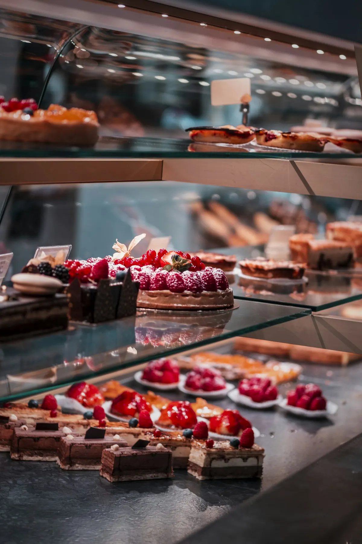 Vitrine réfrigérée avec tartes aux fruits rouges, entremets au chocolat et tartelettes